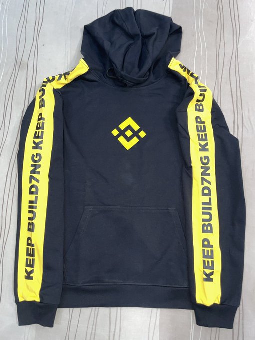 The image features a black hoodie with yellow stripes, which has the word "binance" written across the front in white letters. The hoodie appears to be new and unused, as indicated by its pristine condition. The hoodie also has a zipper running down the front, providing easy access for the wearer. The design of the hoodie is simple yet stylish, with the yellow stripes adding a pop of color that makes it stand out.