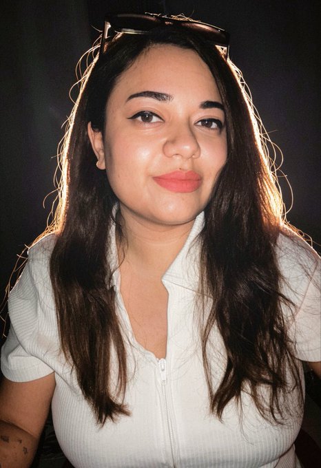 A woman with long dark hair, sunglasses perched on her head, and a white top smiles warmly at the camera, capturing a friendly "GM" vibe that fits the upbeat, optimistic tone of the post about CNPY Network's builder-focused blockchain vision.