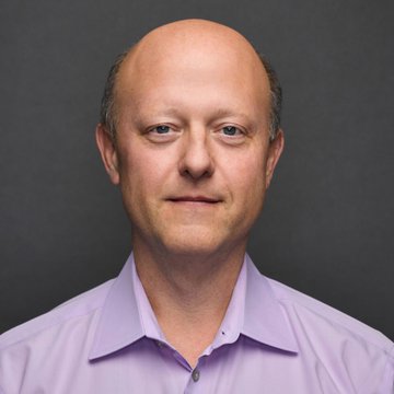 A professional headshot of a balding man in a light purple dress shirt against a gray background, likely a corporate executive related to $CRCL's announcement of receiving US approval to launch a national trust bank.