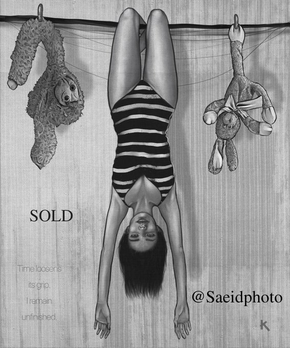 A black and white artistic photograph shows a woman in a striped swimsuit hanging upside down from a line, flanked by a teddy bear and a bunny. Text on the image reads 'SOLD', 'Time loosen its grip. I remain unfinished.', and '@Saeidphoto' with an 'N' logo.