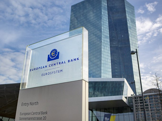 A glass sign in front of a tall skyscraper reads 'EUROPEAN CENTRAL BANK EUROSYSTEM' with 'Entry North' and 'European Central Bank Sonnemannstrasse 20' below.
