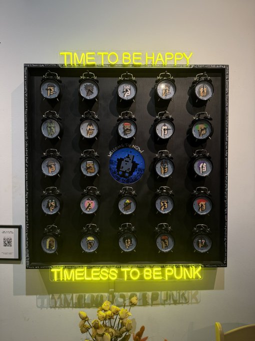 A wall display featuring a grid of pocket watches with neon text above reading 'TIME TO BE HAPPY' and below reading 'TIMELESS TO BE PUNK', with a central decorative element and yellow flowers in the foreground.