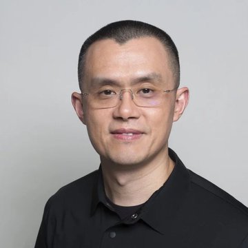 A headshot portrait of an Asian man wearing glasses and a black polo shirt against a gray background.