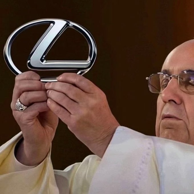 An older man wearing glasses and a light-colored garment holds up a metallic Mercedes-Benz logo emblem, with a ring visible on his finger.