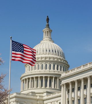 The image shows the U.S. Capitol building with the American flag waving in the foreground, symbolizing the federal government's role in the newly structured Strategic Bitcoin Reserve. The post highlights the White House and Congress's involvement in managing over 328,000 BTC and a proposed bill to acquire 1 million additional Bitcoin over five years.