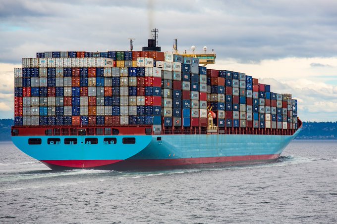 A massive container ship stacked high with colorful shipping containers sails across open waters, visually representing the tangible real-world maritime assets being tokenized "onchain" by @EthraShip to offer investors access to genuine shipping revenue and yields.