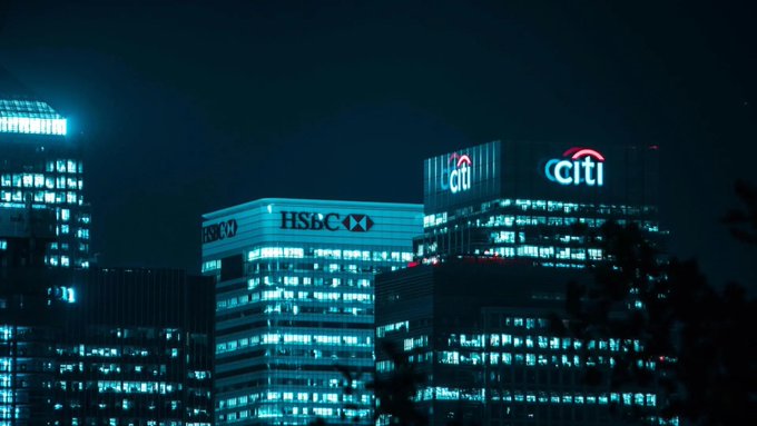 The image shows illuminated skyscrapers at night featuring prominent "HSBC" and "Citi" corporate logos, with the accompanying Vietnamese post discussing Compound DAO's $52 million budget decision and leadership restructuring. The image of major banking institutions appears metaphorically relevant to the discussion of significant financial decisions and the scale of capital involved in the DeFi protocol's restructuring.