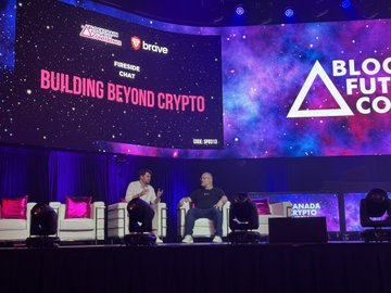 A panel discussion stage at a Blockcha Future Conference with a screen reading 'BUILDING BEYOND CRYPTO' and 'Brave' branding, featuring two men seated in conversation.