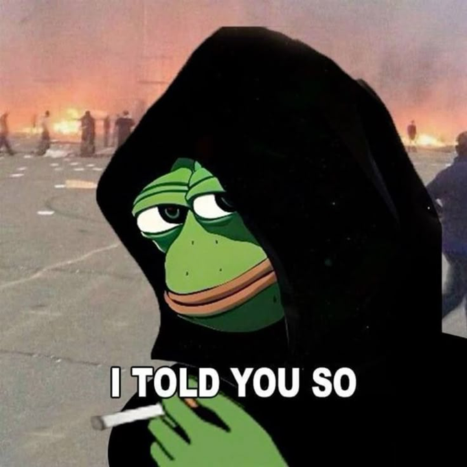 A "told you so" meme featuring the Pepe the Frog character wearing a black hooded cloak and holding a cigarette, with fire and figures visible in the background.