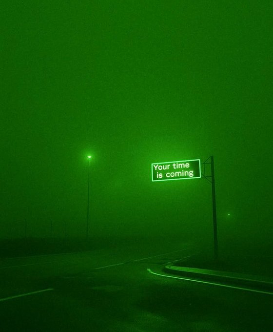 A foggy night street illuminated in green, featuring an illuminated billboard that reads "Your time is coming" alongside $XRP, reinforcing the post's motivational message about XRP.
