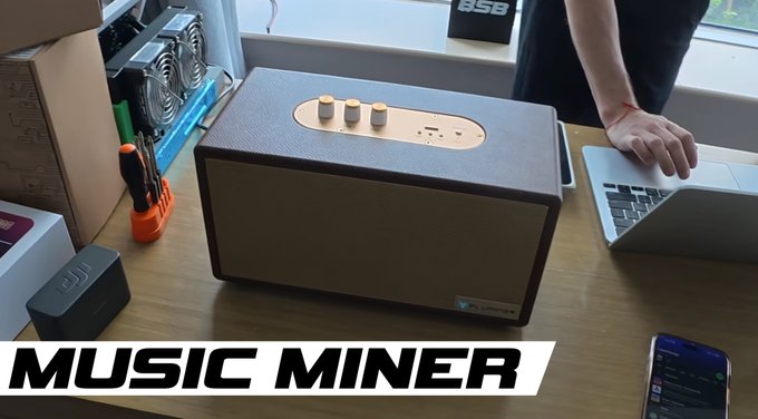 A video still or thumbnail showing a brown Audio Pro speaker on a desk next to a laptop and mining equipment, with the text 'MUSIC MINER' in the bottom left corner.