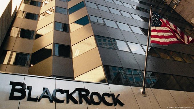 The image features a tall building with an American flag flying from its top, indicating that the building may be located in or near the United States. The building has a sign for "BlackRock" above it, which suggests that the building could be associated with the financial services company BlackRock. Additionally, there is a Bitcoin ETF on display, which implies that the building might also house an investment fund related to cryptocurrencies like Bitcoin. This combination of factors indicates that the image captures a moment where major investors are concentrating their attention and capital around these two asset managers in the market.