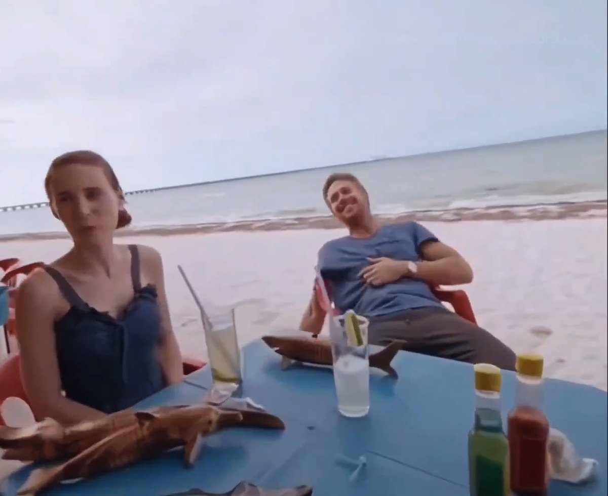 A couple sits at a beach table with drinks and condiments, with the man slumping backward in his chair looking exhausted while the woman stares blankly ahead—mirroring the drained, weary state of crypto traders weathering another tough on-chain week.