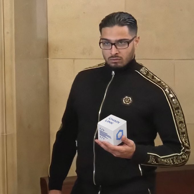 A man in a black tracksuit with gold-patterned sleeves holds up a "CHAINLINK" branded box, visually aligning with the post's critique of institutional finance's tokenization efforts and advocacy for LINK as an alternative path forward.