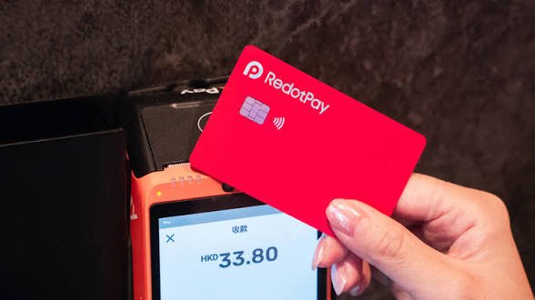 A hand holding a red 'RedotPay' contactless payment card above a payment terminal displaying a transaction amount of HK$33.80.