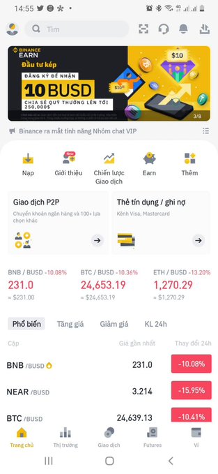 A screenshot of the Binance cryptocurrency app in Vietnamese, showing market prices for BNB/BUSD (-10.08%), BTC/BUSD (-10.36%), and ETH/BUSD (-13.20%), along with a promotional banner for Binance Earn offering up to 10 BUSD.