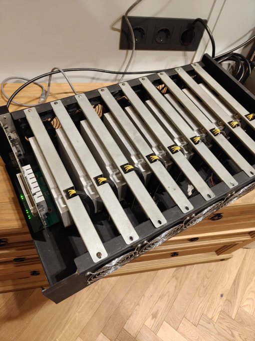 A disassembly reveals nine stripped mining GPUs (P106-100 cards) mounted in parallel on aluminum heatsinks inside a repurposed rack chassis, with visible LED indicators and power cables snaking out the back. The setup embodies the post's "cyberpunk irony"—nine gutted mining cards, lacking display outputs, wired together via USB to harness their combined 54GB of VRAM, all for just $35.