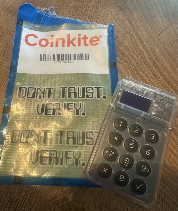 A "Coinkite" tamper-evident security bag with "DON'T TRUST. VERIFY." printed on it sits next to a PIN-protected Coinkite hardware wallet, illustrating the self-custody message in response to a major Bitcoin security incident.