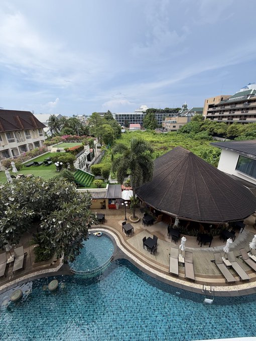 A scenic resort pool area with a thatched-roof pavilion, lounge chairs, and lush tropical landscaping is pictured, though no visible text, tickers, or names appear in the image. The photo seems disconnected from the post, which discusses motivation, AI tools like Claude, and a "100M USD airdrop" tied to the "Lighter's Robinhood campaign."
