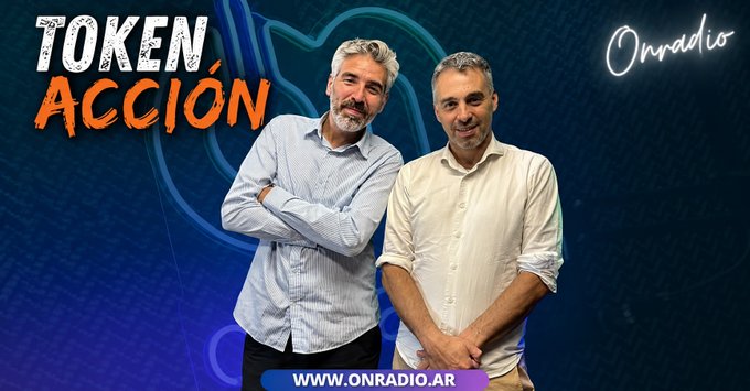 The image features two men standing next to each other, both wearing white shirts. They are positioned against a blue background with neon orange text that reads "Token ACCIÓN" above them. The text also includes the website "www.onradiodigita.com/@OnRadio". This suggests that they might be discussing or promoting an event related to cryptocurrency, specifically tokenization.