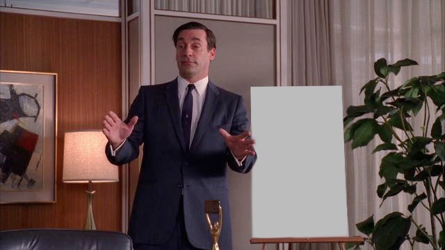 A confident man in a sharp suit stands beside a blank white canvas on an easel, gesturing with his hands as if presenting a great work of art—ironically highlighting the "TITS merch" being sold, perhaps suggesting the merchandise is as empty as the canvas he's pitching.