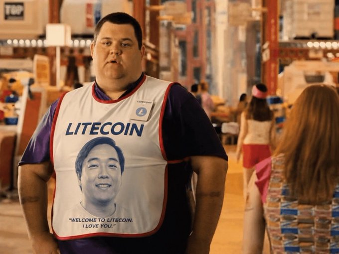 A man in a warehouse wears a white jersey reading "LITECOIN" with a printed face and the caption "WELCOME TO LITECOIN. I LOVE YOU."—mirroring the post's promotional message welcoming viewers to the Litecoin community.