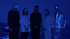 The image features a group of five people standing together, all wearing futuristic outfits that include headpieces or masks. They appear to be posing for a photo against a blue background with white text. The caption of the image reads "the five curators have been selected! we are getting in touch today and make the announcement tomorrow excited already!".