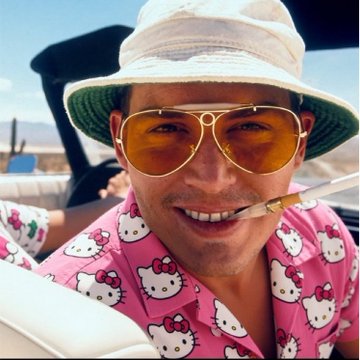 A man wearing a pink Hello Kitty shirt, aviator sunglasses, and a bucket hat smiles with a cigarette in his mouth in a brightly lit, sunny setting.