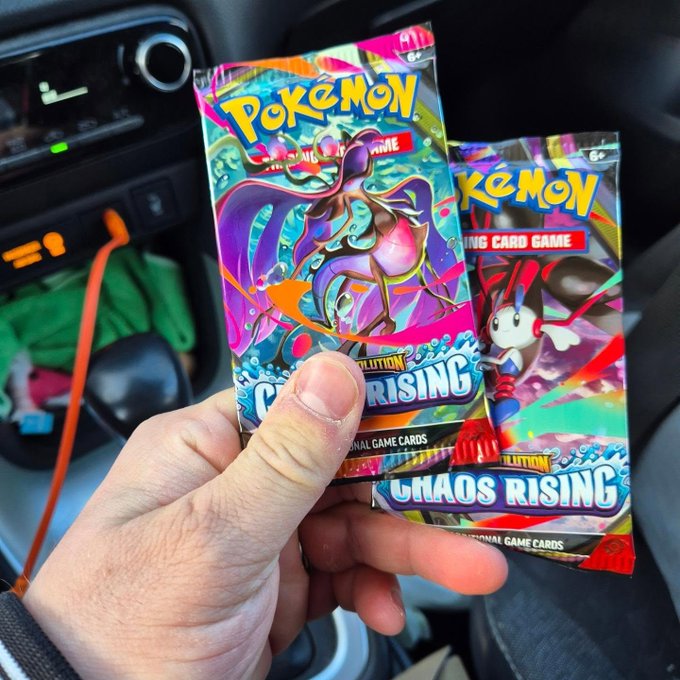 A hand holds up two Pokémon TCG "Chaos Rising" booster packs, featuring colorful artwork with "Pokémon Trading Card Game" and "Evolution Chaos Rising" text, photographed inside a car. The image likely accompanies a post about encountering counterfeit or defective cards, as the seller responds that they are addressing the issues.
