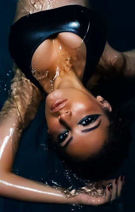An artistic photograph shows a woman with dramatic makeup submerged in water, her body draped in black fabric.