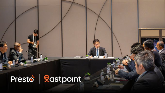 Corporate meeting photograph showing executives seated around a conference table, with 'Presto' and 'eastpoint' logos displayed in the foreground.