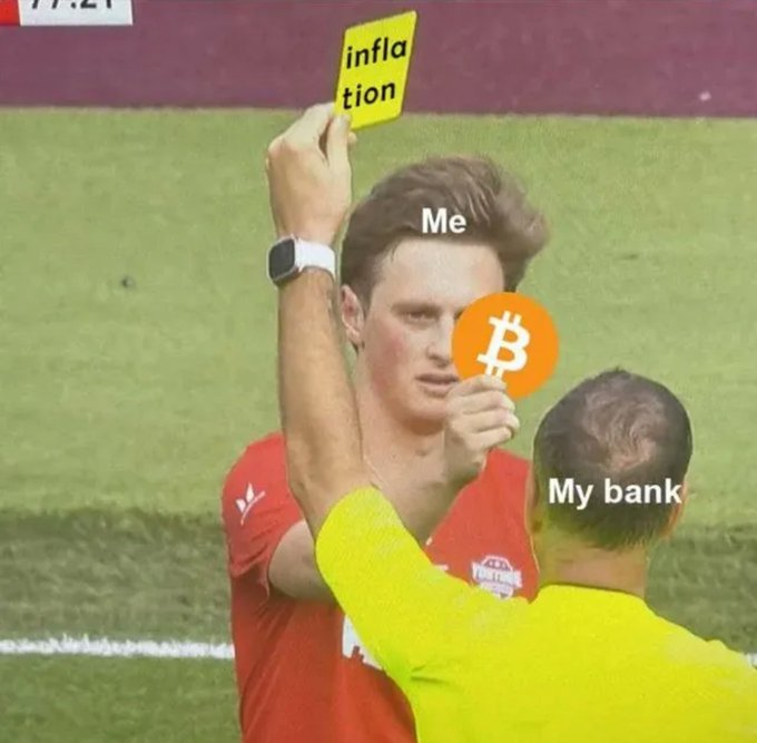 A soccer referee holds up a yellow "inflation" card toward a player labeled "Me," while the referee himself is labeled "My bank" and has a Bitcoin logo covering his face. The meme humorously depicts the user's bank acting as the enforcer of inflation, issuing the penalty against the person who prefers Bitcoin as an alternative.