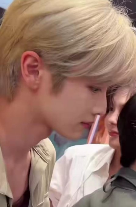 A close-up photo of a young man with blonde hair and another person with dark hair, appearing to be in close proximity.