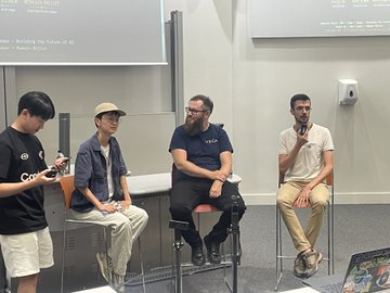 A panel discussion at an academic event with three speakers seated on stools, including one wearing a "VISA" branded shirt, alongside a staff member in a Kaspa-themed t-shirt and cap, likely representing the Kaspa blockchain community at a tech or university gathering.