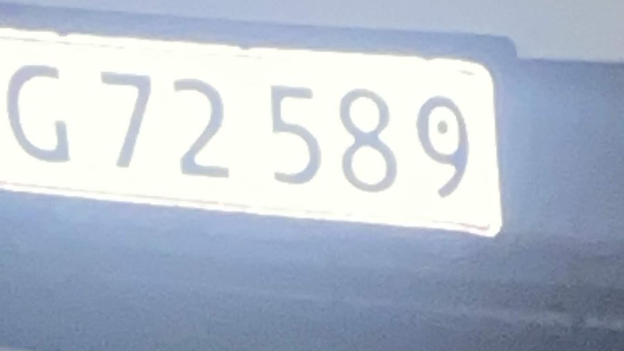 A close-up of a white license plate with the text 'G 72 589' affixed to a blue vehicle.