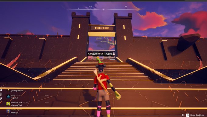 A Fortnite screenshot showing a player character in a red and yellow outfit standing on glowing golden steps in front of a structure called 'THE CUBE' with the username 'devastatin_dave' visible.