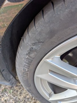 A close-up photo shows a severely damaged and worn Continental tire mounted on a silver alloy wheel, with visible cracking and deterioration on the sidewall.