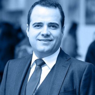 A professional portrait of Özgür Demirtaş in a suit and tie, presented in a blue-tinted filter. The caption accompanies his quote predicting that 99% of cryptocurrencies will become worthless, lending a serious, business-like air to his bearish forecast on the crypto market.