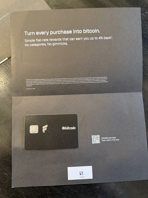 The image features an open envelope with a black credit card inside, which appears to be a Bitcoin wallet. The envelope has a white label that says "Turn every purchase into Bitcoin" written on it. There are also some text elements on the envelope, such as "No categories, no judgments".