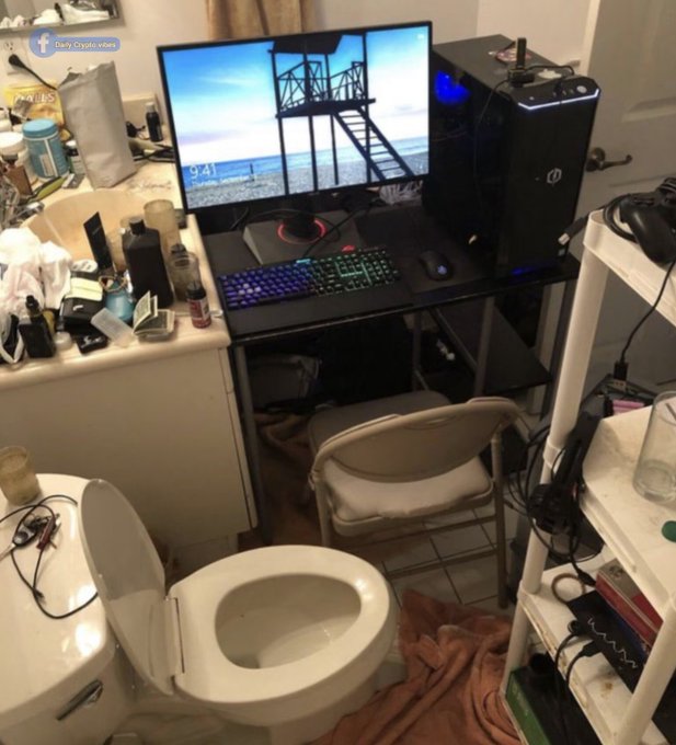 The post is humorously titled "Rate my new trading setup" as the image shows a desktop gaming/PC setup with a curved monitor displaying a beach scene, RGB keyboard, and tower PC that has been set up directly next to and over a toilet in a small bathroom.

Visible text on the monitor reads "9:41" (likely a screensaver time), and a watermark in the top-left corner says "Charli Crypto Whore."