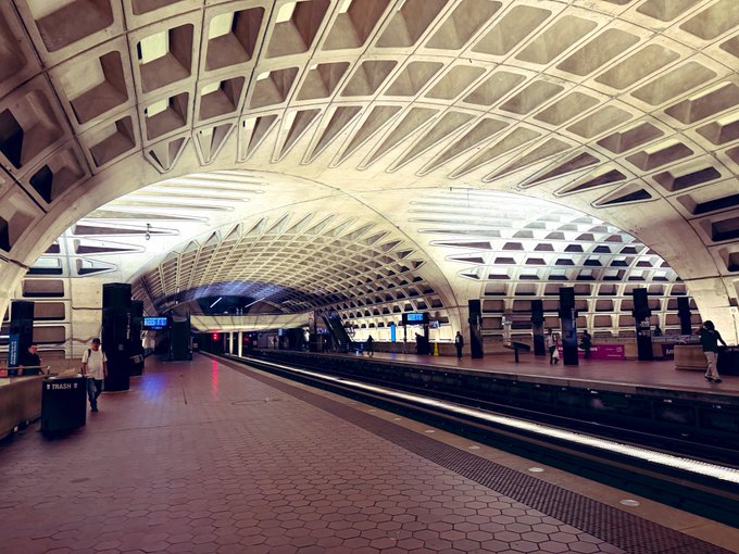 A Washington DC Metro station featuring the distinctive coffered concrete vault ceiling designed by Harry Weese, with an empty platform and tracks extending into the distance.