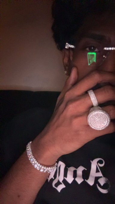 A man shows off his diamond-encrusted ring and matching bracelet while taking a close-up selfie, with "DOS" partially visible on his shirt—capturing the kind of flashy flex worthy of a contest winner claiming 5 SOL.