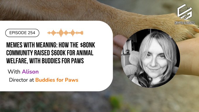 The image features a woman's hand holding a dog, with the background blurred out. The main focus of the image is the woman's hand and the dog, both appearing prominently against each other. There are no texts or other objects present in the image.