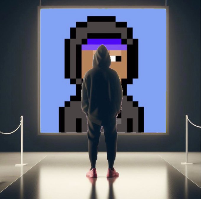A person in a hoodie standing in front of a large illuminated pixel art portrait in a gallery-like setting with stanchions.