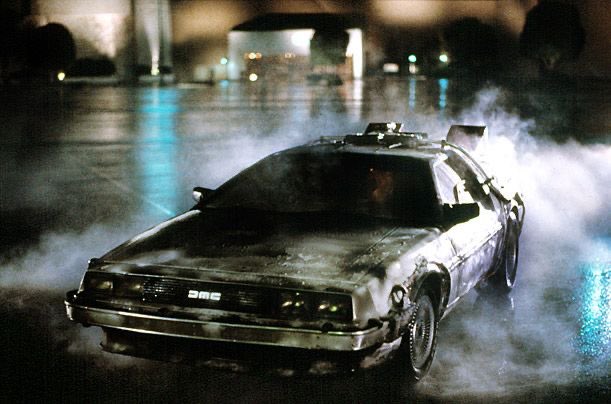 A modified DeLorean car with 'DMC' on the front grille speeds through a dark, misty area with smoke billowing around it.