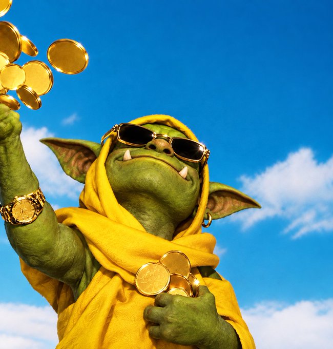 A green goblin character wearing sunglasses and a yellow robe holds up gold coins against a blue sky, accessorized with a gold chain and watch.