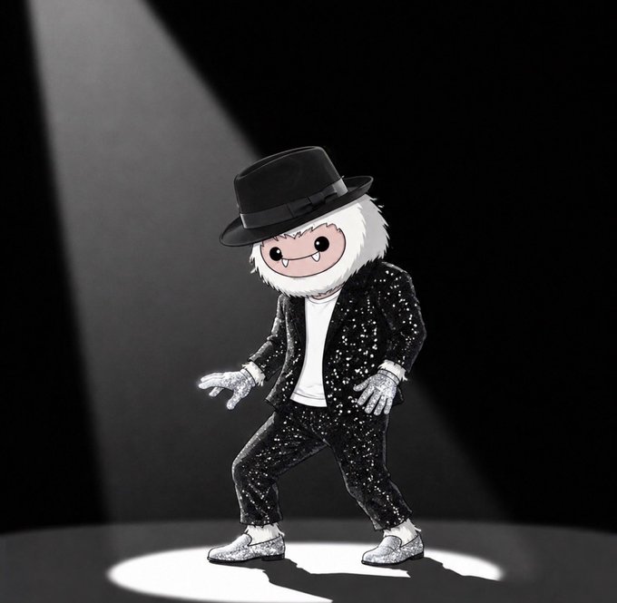 A black and white photo of a plush toy with a white furry face and fangs, wearing a black fedora and a sparkly black suit, posed in a dance stance under a spotlight.