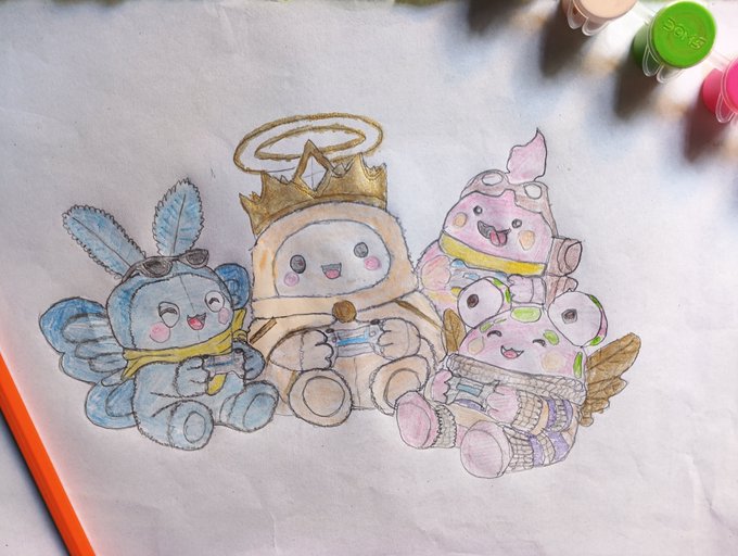 A hand-drawn sketch on white paper depicts three cute chibi-style characters: a blue creature with rabbit ears, a crowned figure holding a slice of cake, and a pink creature with goggles.