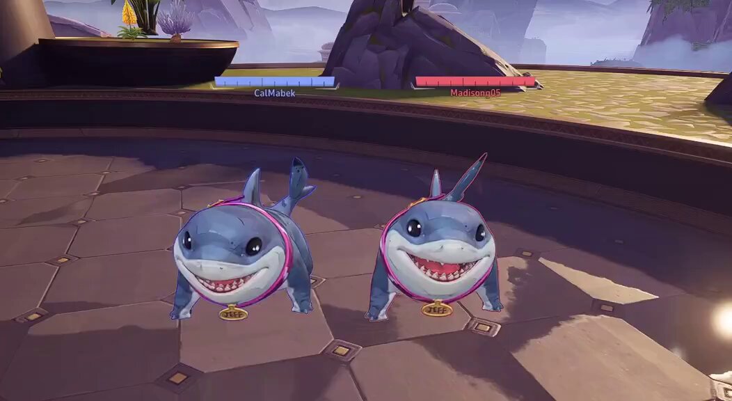 ursa and ursa, two blue sharks with pink accents, stand on a gray platform with a rocky cliff backdrop.