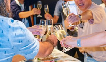 Several people raise champagne flutes in a celebratory toast at what appears to be a social gathering or event.